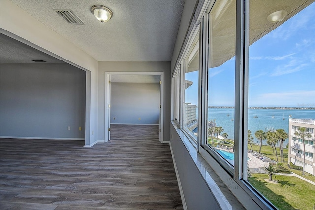 interior space with a water view, dark hardwood / wood-style floors, and a textured ceiling