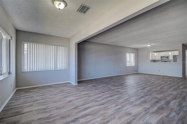 unfurnished living room featuring hardwood / wood-style floors and a textured ceiling