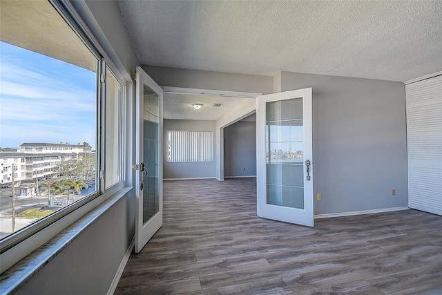 unfurnished room featuring a textured ceiling, dark hardwood / wood-style flooring, and french doors