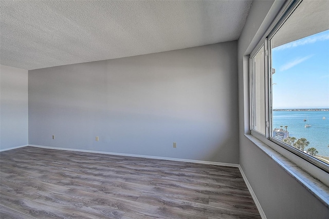 spare room featuring hardwood / wood-style flooring, a water view, and a textured ceiling