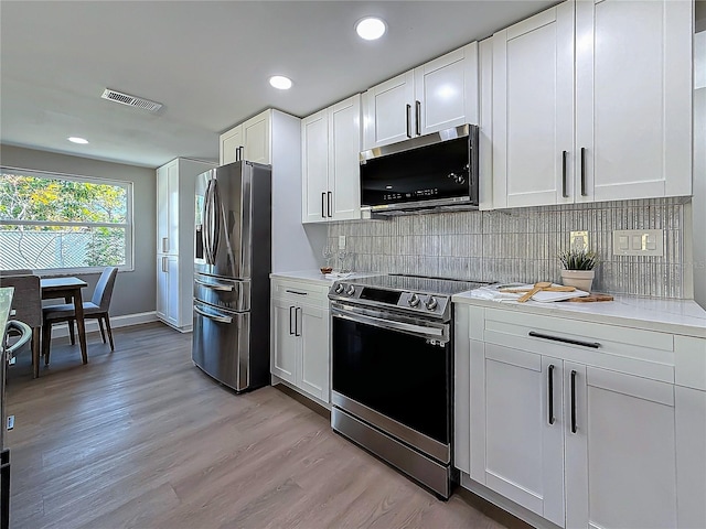 kitchen featuring tasteful backsplash, light wood-type flooring, white cabinets, and appliances with stainless steel finishes