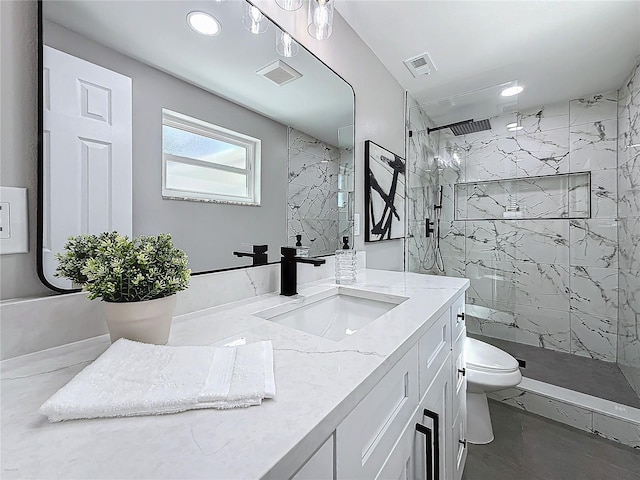 bathroom featuring vanity, a tile shower, and toilet