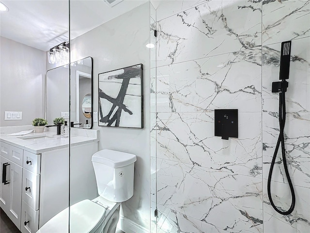 bathroom with a tile shower, vanity, and toilet