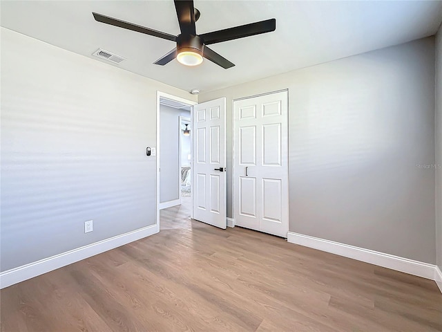 unfurnished bedroom featuring ceiling fan, a closet, and light wood-type flooring