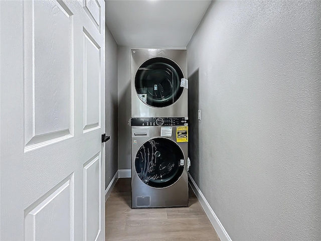 laundry room with stacked washer / dryer and light hardwood / wood-style flooring