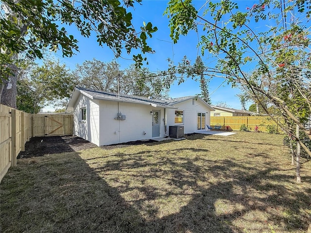 rear view of property featuring a yard, central AC unit, and a patio area