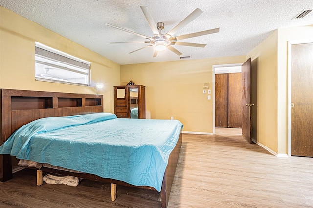 bedroom with ceiling fan, a textured ceiling, and light hardwood / wood-style flooring