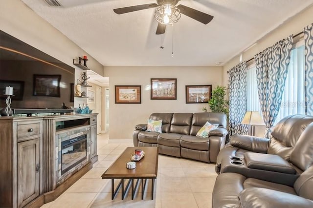 living room featuring a tile fireplace, ceiling fan, and light tile patterned flooring