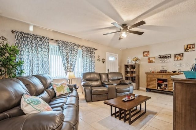 living room featuring light tile patterned floors, a textured ceiling, and ceiling fan