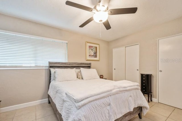 bedroom featuring two closets, light tile patterned floors, and ceiling fan