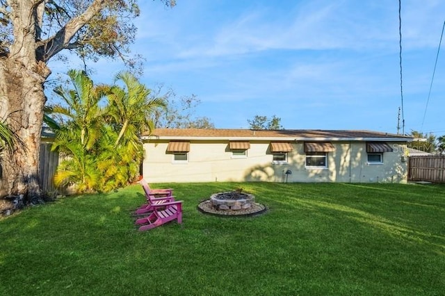 rear view of house with a lawn and an outdoor fire pit