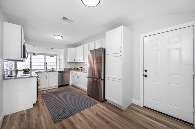 kitchen featuring white cabinetry, sink, backsplash, hardwood / wood-style flooring, and stainless steel appliances