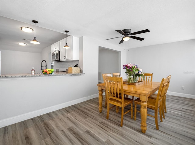 dining room with light wood-style floors, ceiling fan, and baseboards