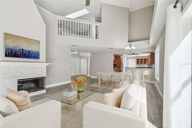 living room with light hardwood / wood-style flooring, a notable chandelier, a towering ceiling, and a fireplace