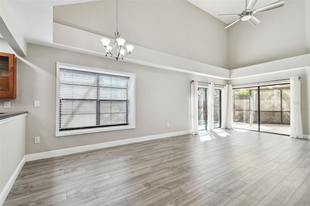 interior space featuring ceiling fan with notable chandelier, high vaulted ceiling, and light hardwood / wood-style floors