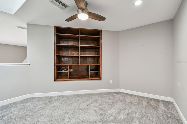 carpeted empty room featuring ceiling fan and a skylight