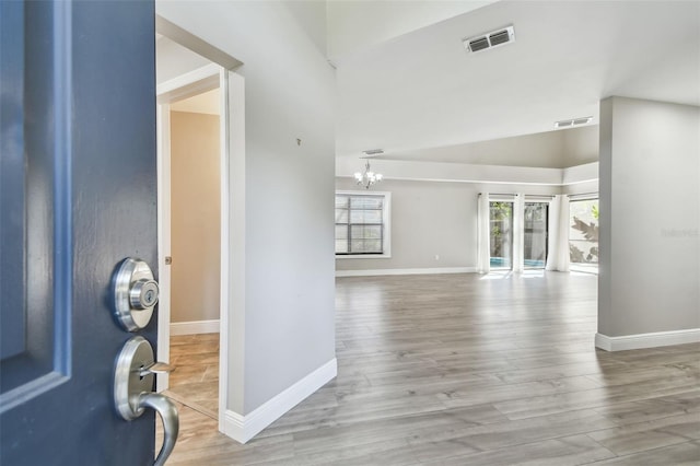 entrance foyer with vaulted ceiling, a notable chandelier, and light hardwood / wood-style floors