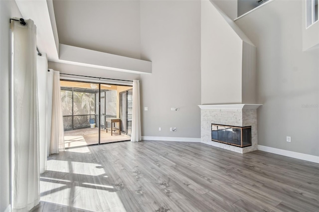 unfurnished living room featuring hardwood / wood-style flooring, a fireplace, and a high ceiling