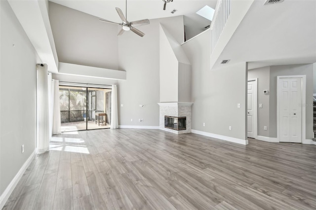 unfurnished living room featuring ceiling fan, a towering ceiling, and light hardwood / wood-style floors