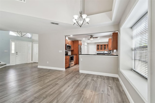 interior space featuring ceiling fan with notable chandelier and light hardwood / wood-style flooring