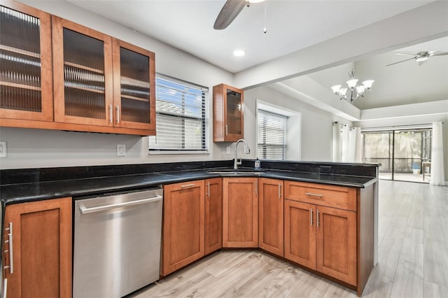 kitchen with stainless steel dishwasher, a healthy amount of sunlight, sink, and dark stone countertops