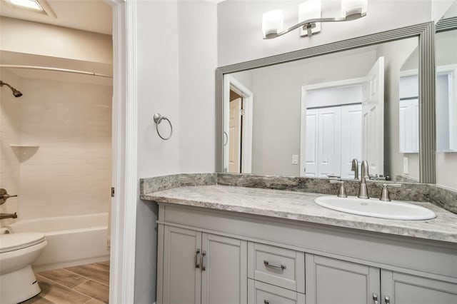 full bathroom featuring tiled shower / bath, vanity, and toilet