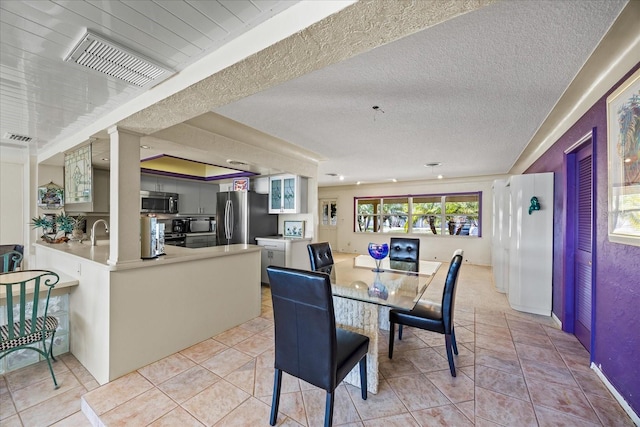 dining space with light tile patterned floors, sink, and a textured ceiling