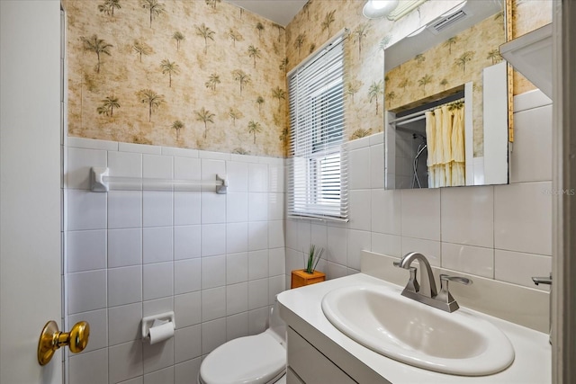 bathroom featuring vanity, tile walls, and toilet