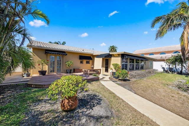 back of property featuring a lawn, a deck, and french doors