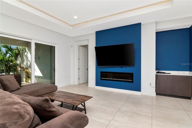 living room with a fireplace, light tile patterned flooring, and a tray ceiling