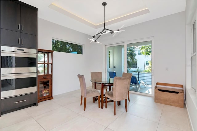 tiled dining space featuring a raised ceiling and a notable chandelier