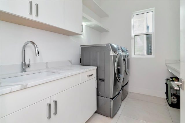 laundry room featuring sink, cabinets, light tile patterned flooring, and washing machine and clothes dryer