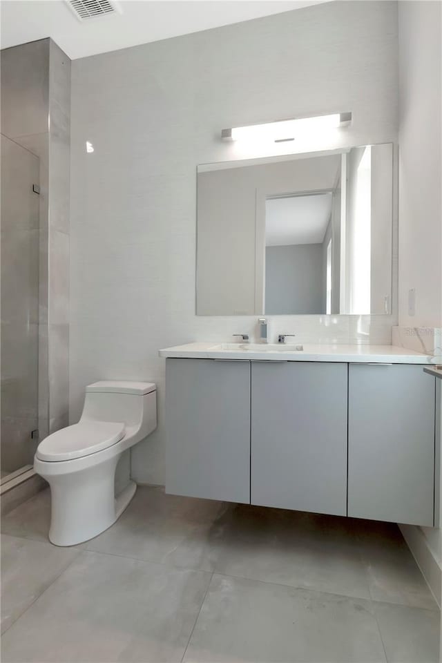 bathroom with tile patterned flooring, vanity, a shower with door, and toilet