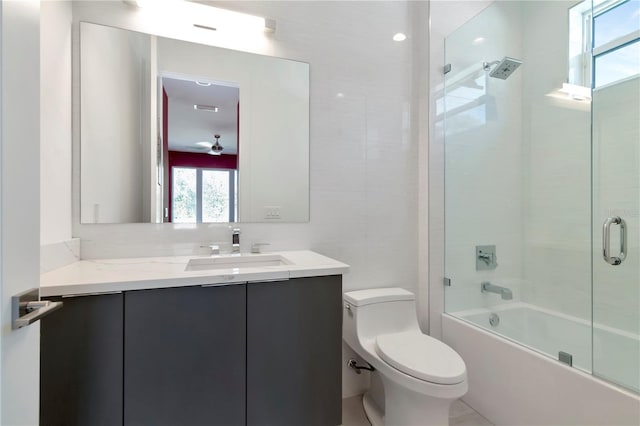 full bathroom with toilet, bath / shower combo with glass door, vanity, ceiling fan, and backsplash