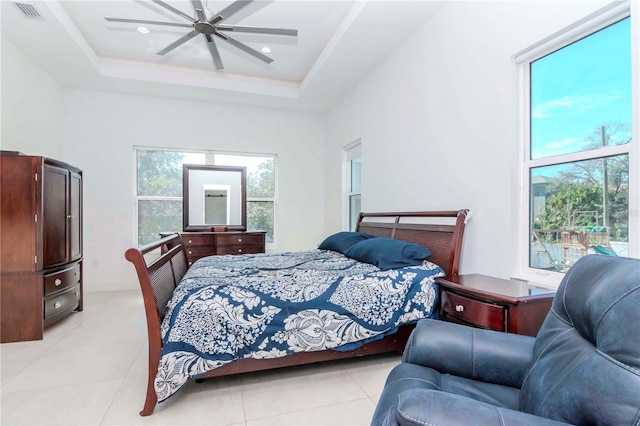 tiled bedroom with a raised ceiling and ceiling fan