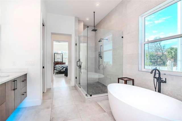 bathroom featuring tile patterned floors, independent shower and bath, tile walls, and vanity