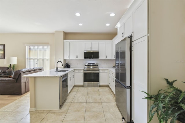 kitchen featuring sink, light tile patterned floors, appliances with stainless steel finishes, white cabinetry, and kitchen peninsula