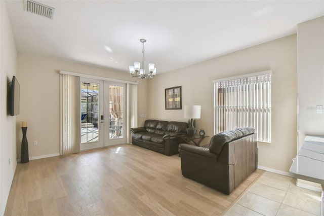 living room with a notable chandelier, light wood-type flooring, and french doors