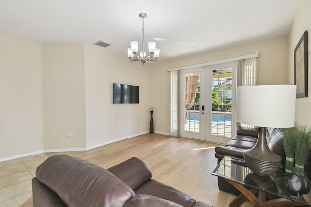 living room featuring french doors, a chandelier, and light wood-type flooring