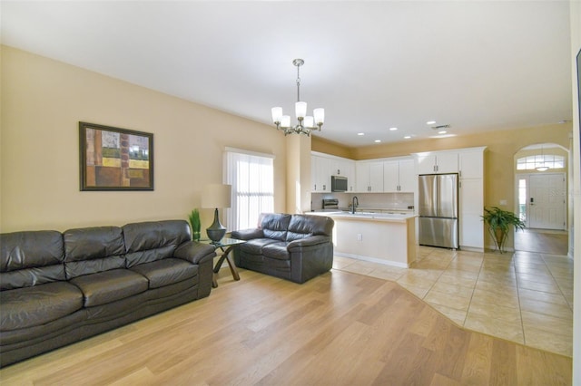 living room with an inviting chandelier, sink, and light hardwood / wood-style flooring