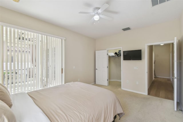 carpeted bedroom featuring access to exterior, a walk in closet, and ceiling fan