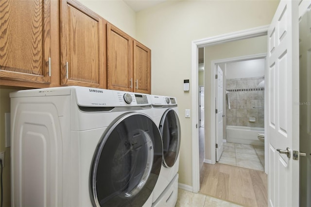 laundry room with cabinets, washer and clothes dryer, and light tile patterned floors