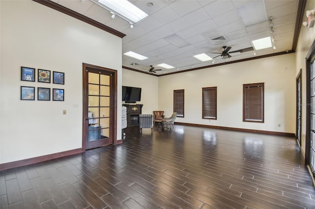 empty room featuring dark hardwood / wood-style flooring, ornamental molding, track lighting, and ceiling fan