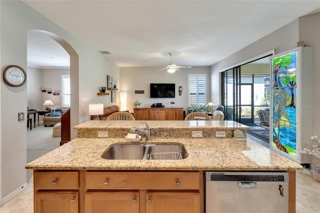 kitchen with dishwasher, sink, light stone countertops, and a center island with sink