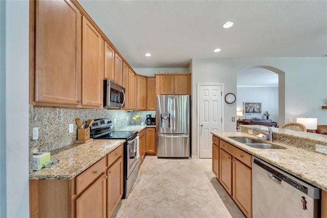 kitchen with light stone countertops, decorative backsplash, stainless steel appliances, and sink