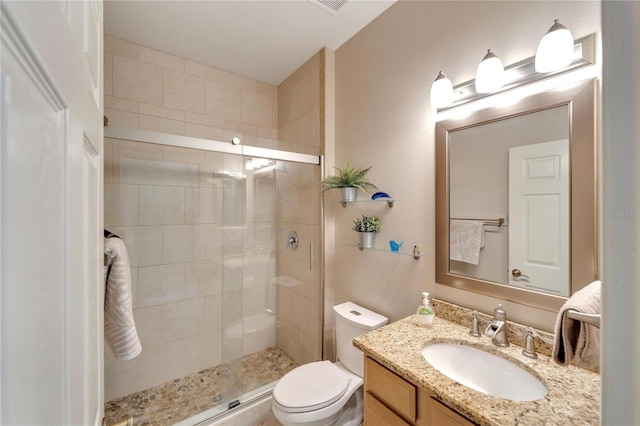 bathroom featuring a shower with door, vanity, and toilet