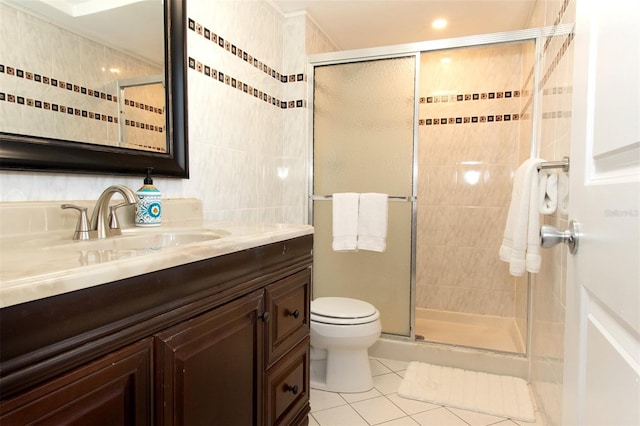 bathroom with toilet, a shower with shower door, tile walls, vanity, and tile patterned flooring