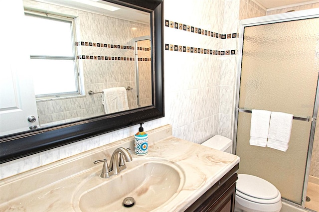 bathroom featuring vanity, toilet, an enclosed shower, and tile walls