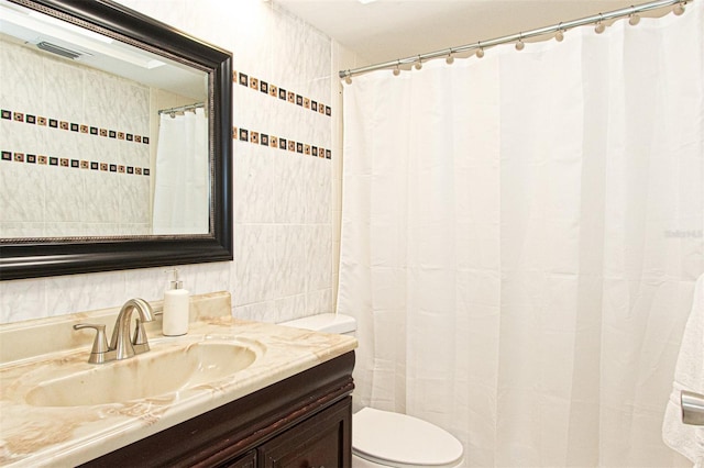 bathroom with vanity, toilet, and tile walls