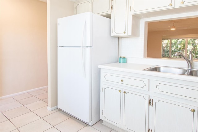 kitchen with sink, tasteful backsplash, light tile patterned floors, white fridge, and white cabinets